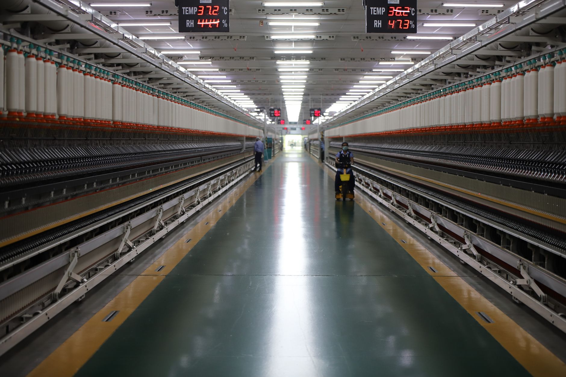 Workers monitor manufacturing equipment as U.S. business investment data shows a pullback in core capital goods orders.