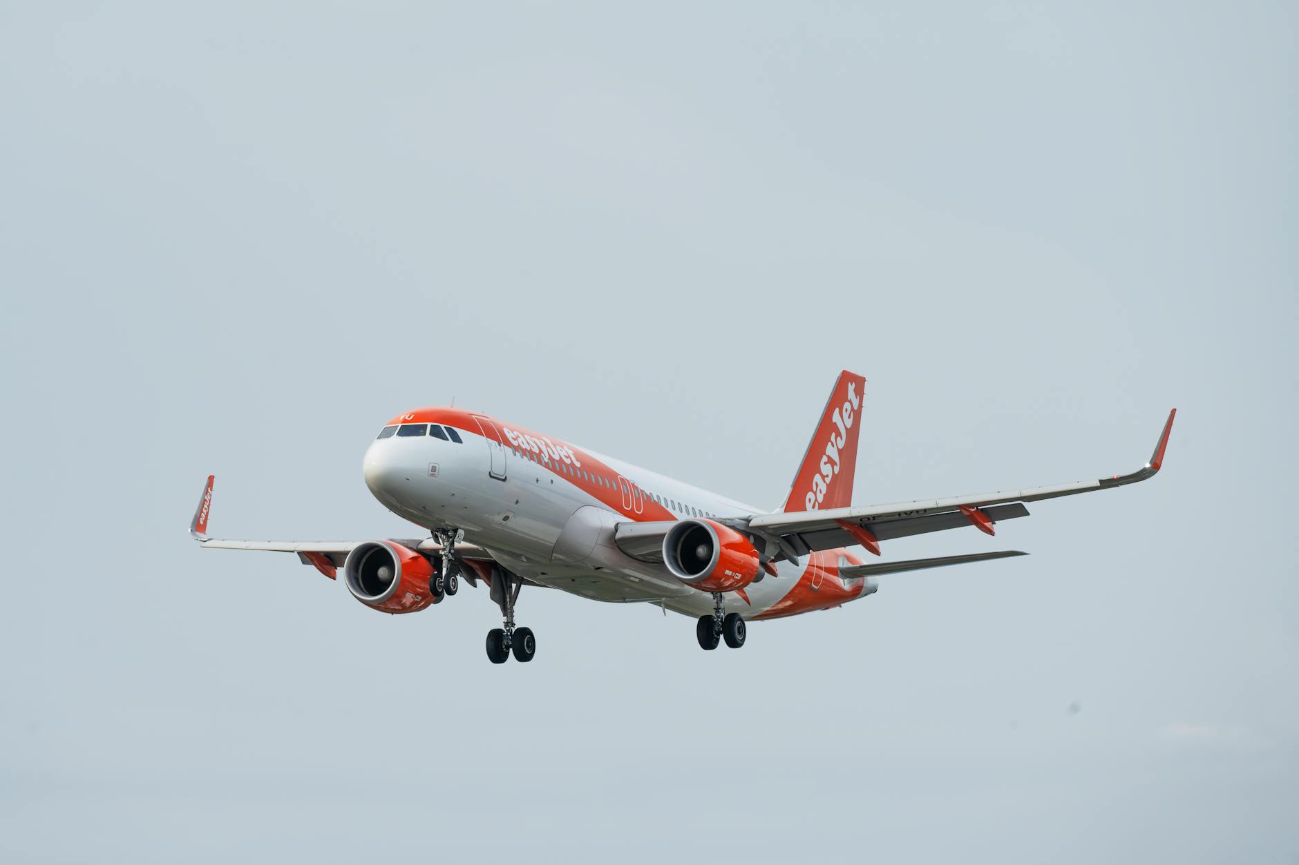An easyJet aircraft is parked at an airport as passengers move through a terminal during the busy travel season.